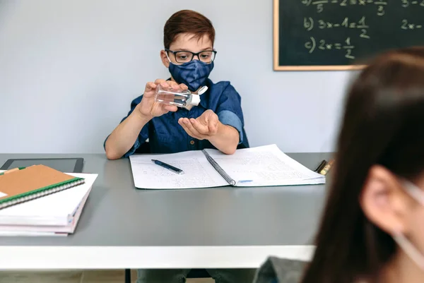 手の消毒剤を適用顔のマスクを持つ学生 — ストック写真