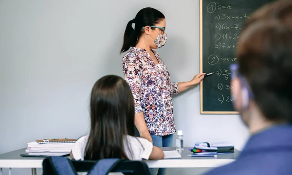 Professor com máscara explicando exercícios em aula de matemática — Fotografia de Stock