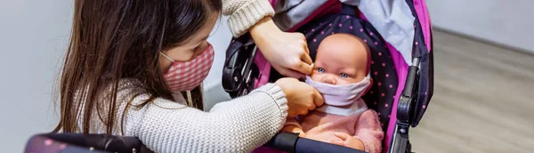 Meisje met gezichtsmasker zet masker op haar baby pop — Stockfoto