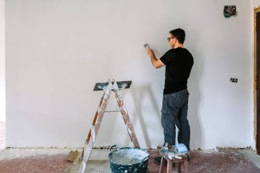 Duvarı spatulayla tamir eden tuğla ustası.