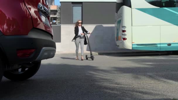 Женщина переезжает на электрическом скутере и открывает багажник автомобиля — стоковое видео