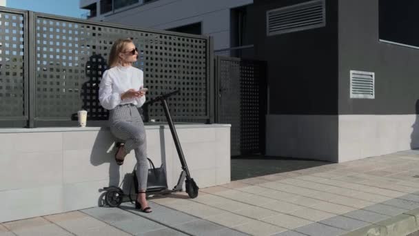 Geschäftsfrau mit Handy und ihrem Roller neben — Stockvideo