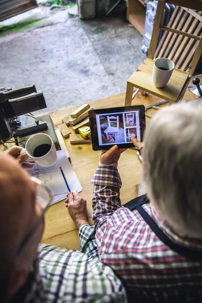 Coppia anziana in una falegnameria alla ricerca di tablet — Foto Stock