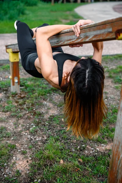 Sportswoman training hanging on a wooden bar — Stock Photo, Image