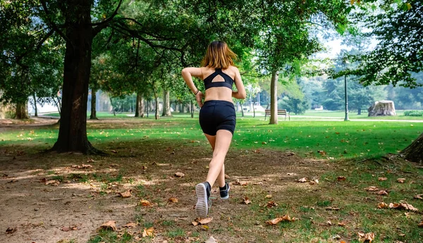 Atleta feminina correndo por um parque — Fotografia de Stock