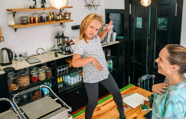 Mother watching her dancing daughter while working in a coffee shop. — Stock Photo, Image