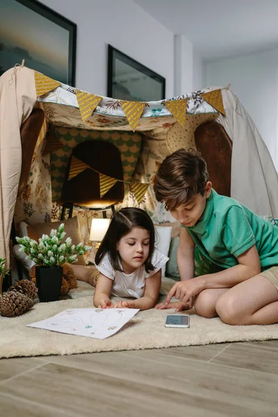 Hermanos jugando en una carpa en la sala de estar —  Fotos de Stock