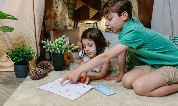 Los niños jugando juego de caza del tesoro en una tienda de campaña en casa —  Fotos de Stock