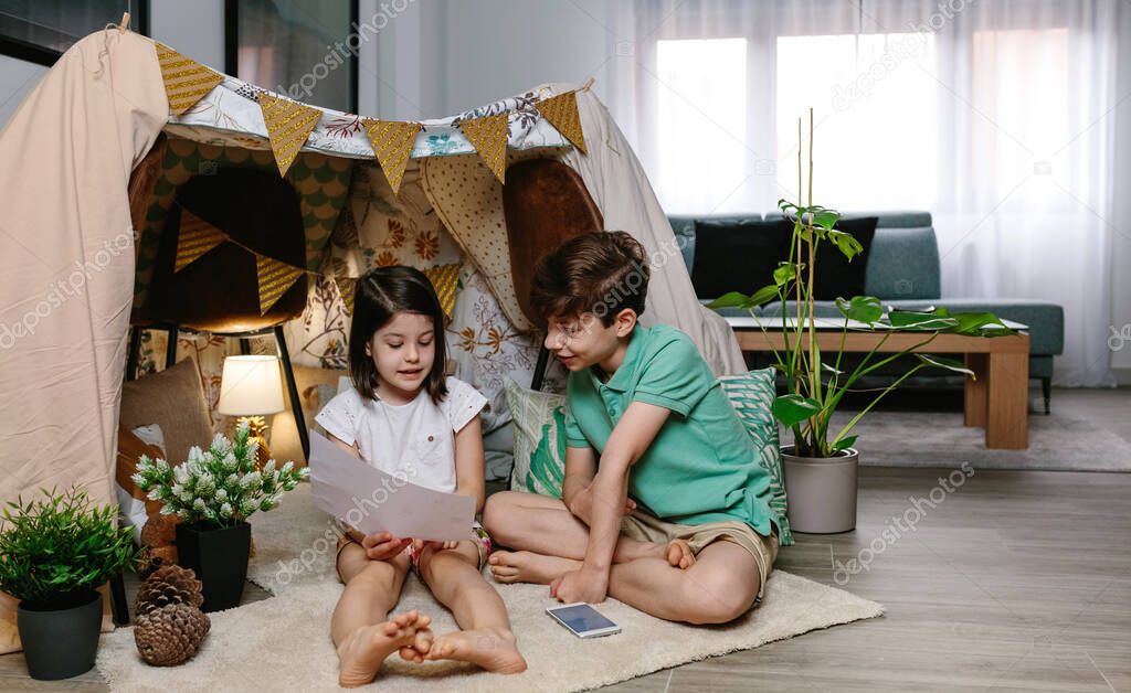 Boy and girl playing in a diy tent at home