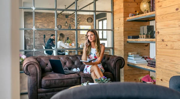 Geschäftsfrau arbeitet mit Laptop und telefoniert auf dem Sofa — Stockfoto