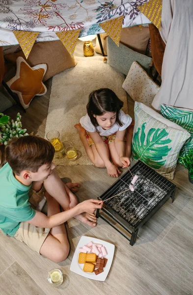 Hermanos acampando en casa tostando malvaviscos —  Fotos de Stock