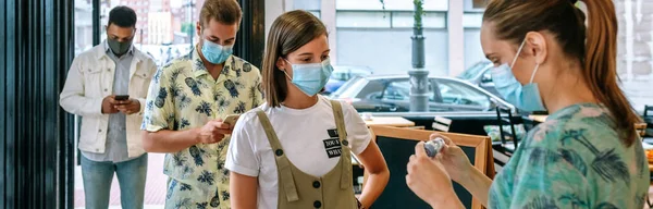 Geschäftsinhaberin schaut auf das Thermometer, das ihre Mitarbeiter überprüft — Stockfoto