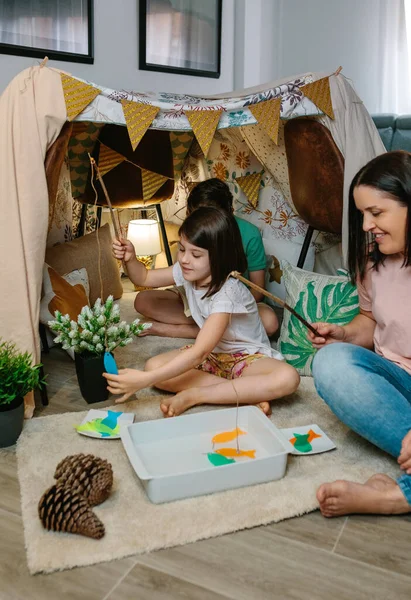 Happy mother and daughter camping at home playing diy fishing game — Stock Photo, Image