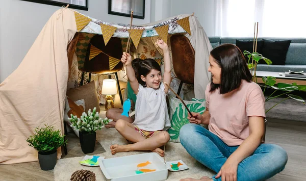 Chica feliz de ganar a su madre en un juego de pesca — Foto de Stock