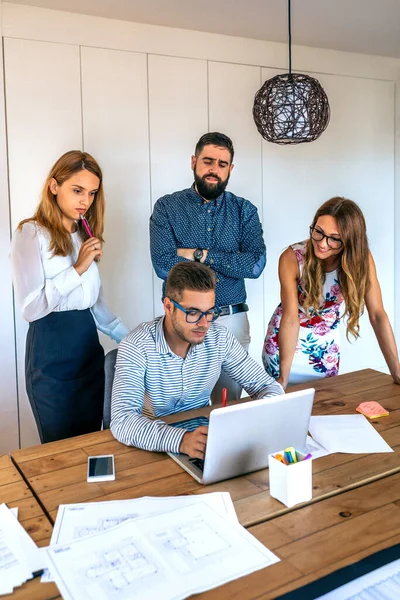 Empresários em uma reunião de pé revisando um projeto no laptop — Fotografia de Stock