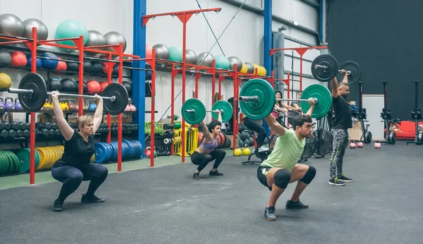 Personas que practican levantamiento de pesas levantando pesas en el gimnasio — Foto de Stock