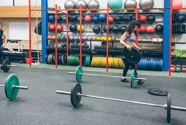 Woman picking up weightlifting discs — 스톡 사진