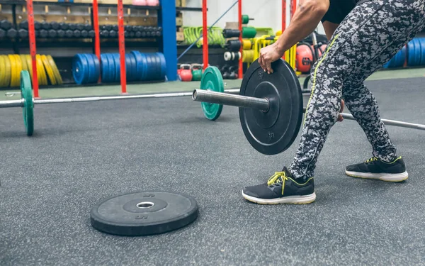 Man crouching changing the discs of the weightlifting bar — Photo