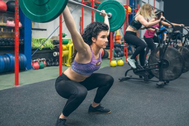 Spor salonunda ağırlık kaldıran bir kadın.