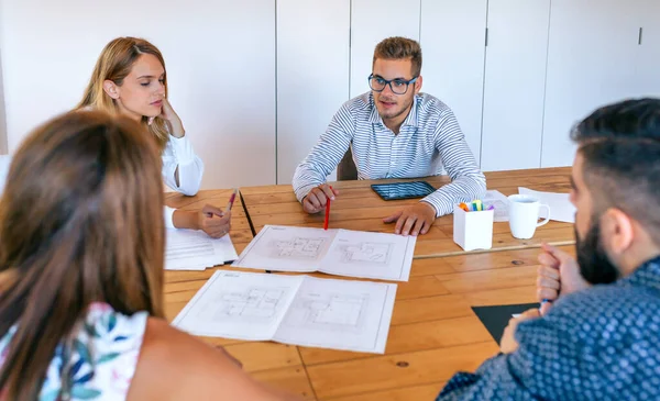 Empresários em uma reunião de trabalho olhando para desenhos de construção — Fotografia de Stock