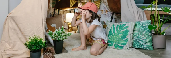 Dziewczyna bawiąca się tekturową lornetką podczas kempingu w domu — Zdjęcie stockowe
