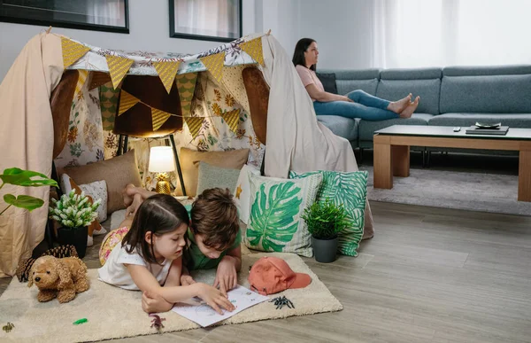 Children playing camping at home while their mother watches TV — Stock Photo, Image