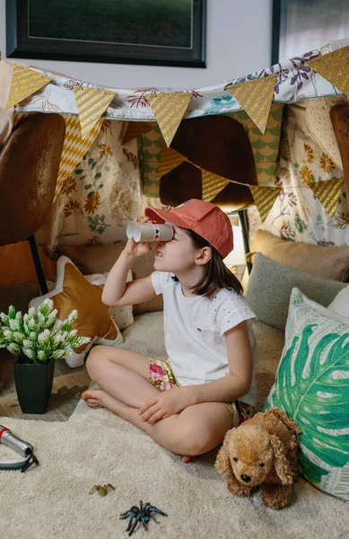 Chica jugando con binoculares de cartón mientras acampa en casa — Foto de Stock