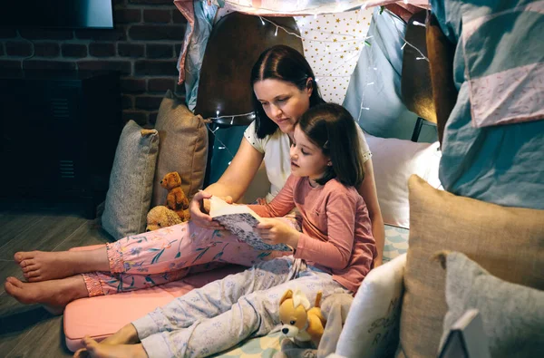 Matka i córka czytają książkę w małym namiocie — Zdjęcie stockowe