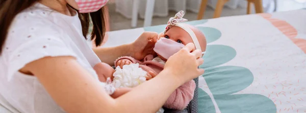 Maskeli kız bebeğine küçük bir maske takıyor. — Stok fotoğraf