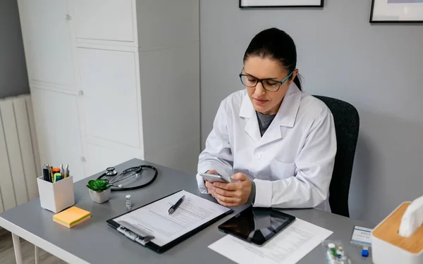 근무중에 핸드폰을 사용하는 여성 의사 — 스톡 사진