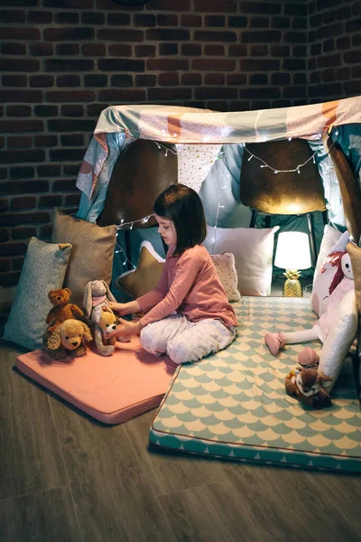 Menina brincando com animais de pelúcia em um teepee — Fotografia de Stock