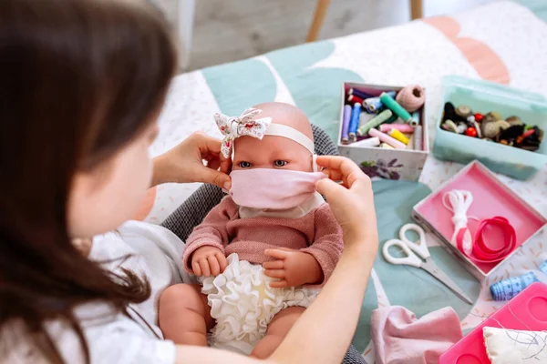 Mädchen versucht auf ihrer Puppe eine Maske, die sie näht — Stockfoto