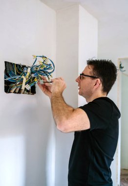 Elektrikçi bir evin elektrik tesisatı üzerinde çalışıyor.