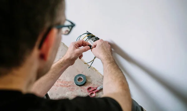 Elektrikçi bir evin elektrik tesisatı üzerinde çalışıyor. — Stok fotoğraf