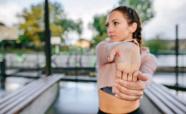 Mladá žena sportovec natahování ruce a zápěstí venku — Stock fotografie