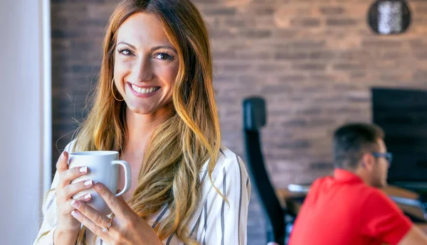 Glad affärskvinna tittar på kameran med en kopp kaffe — Stockfoto