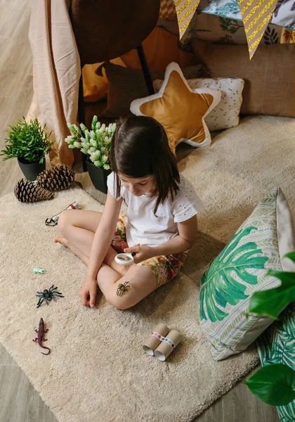 Chica jugando observando insectos de juguete con una lupa — Foto de Stock