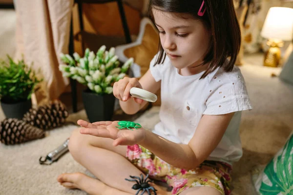 Chica jugando observando insectos de juguete con una lupa —  Fotos de Stock