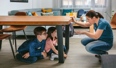 Anne çocuklarına depremde kendilerini nasıl koruyacaklarını anlatıyor.
