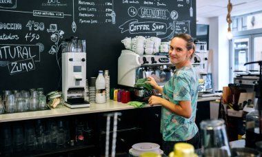 Gülümseyen garson kahve makinesini temizliyor.