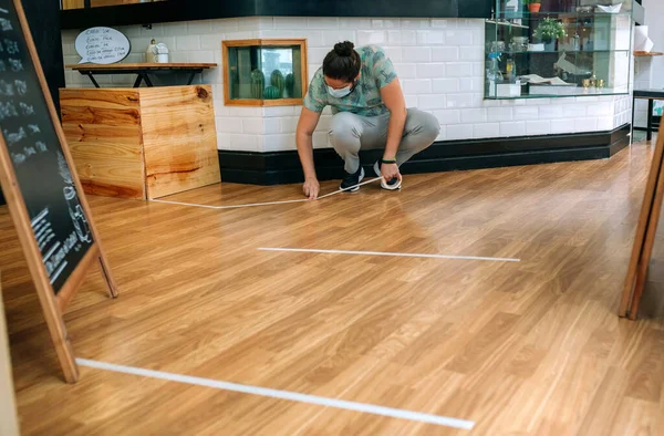 Сотрудник кофейни ставит метки на полу — стоковое фото