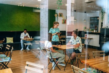 Garson tabletle müşteri siparişi alıyor.