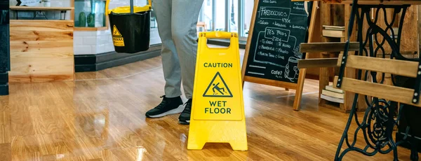 Arbetstagare som placerar våt golvskylt efter moppning — Stockfoto