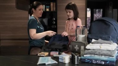 Anne kızıyla acil sırt çantası hazırlıyor.