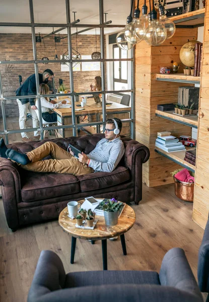 Empresario acostado en un sofá de oficina con tablet — Foto de Stock