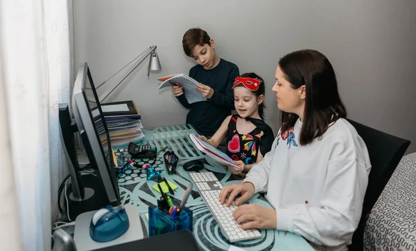 Woman teleworking and reviewing her childrens homewor — Stock Photo, Image