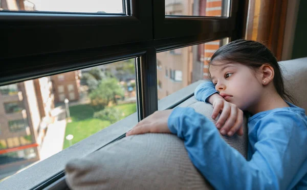 Menina triste olhando pela janela — Fotografia de Stock