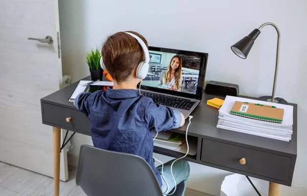 Onherkenbare jongen met hoofdtelefoon die thuis les krijgt met laptop uit zijn slaapkamer — Stockfoto