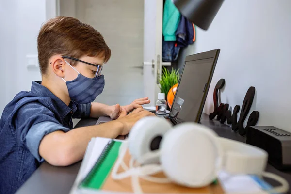 Έφηβος με μάσκα προσώπου κάνει την εργασία με το laptop — Φωτογραφία Αρχείου