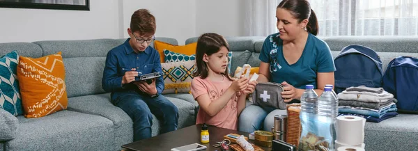 Mother preparing emergency backpack with her children — Stock Photo, Image